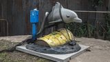 Delfin in Öl  Was sehen wir? Natürlich kein Ölgemälde von Flipper, sondern eine Kirmesattraktion für Kinder: ein Delfin zum Reiten – aber verheddert in einem Fischernetz und umgeben von Erdöl. Woher das kommt, daran lässt Banksy keinen Zweifel. Auf dem Fass prangt groß das Firmenlogo des Energiekonzerns BP (British Pertroleum).  Was will uns Banksy damit sagen? Er stellte seinen Flipper 2013 ausgerechnet an der Promenade im britischen Seebad Brighton auf, wo täglich Tausende Touristen entlangschlendern. Das Ding ratterte dort pausenlos vor sich hin – üblicherweise muss man eine Münze einwerfen – und lockte so zahllose Kinder an. Was zu einigen Fragen geführt haben muss: "Mama, warum guckt der Delfin so traurig?" – "Papa, wer ist BP und was machen die?" – "Mama, warum ist BP so böse?" Noch Fragen, was uns Banksy sagen will?