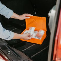 Junge Frau mit Auto Erste-Hilfe-Kit-Box