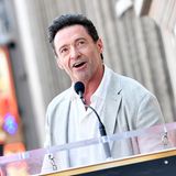 Hugh Jackman schaut an der Kamera vorbei und spricht in ein Mikro.