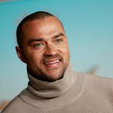 Jesse Williams schaut an der Kamera vorbei und lächelt.