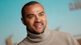 Jesse Williams schaut an der Kamera vorbei und lächelt.