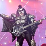 Gene Simmons steht verkleidet auf der Bühne und hält einen Bass.