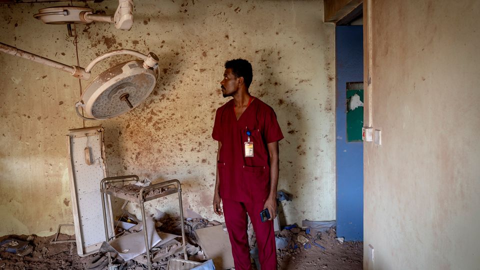Ein Pfleger in rotem Hemd steht vor den zerstörten Überresten eines Operationsraums