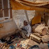 Ein Schuhverkäufer sitzt zwischen Trümmern