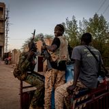 Drei Soldaten stehen auf einem Pick-up-Truck.