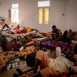 Sieben Männer liegen auf Betten in einem Raum