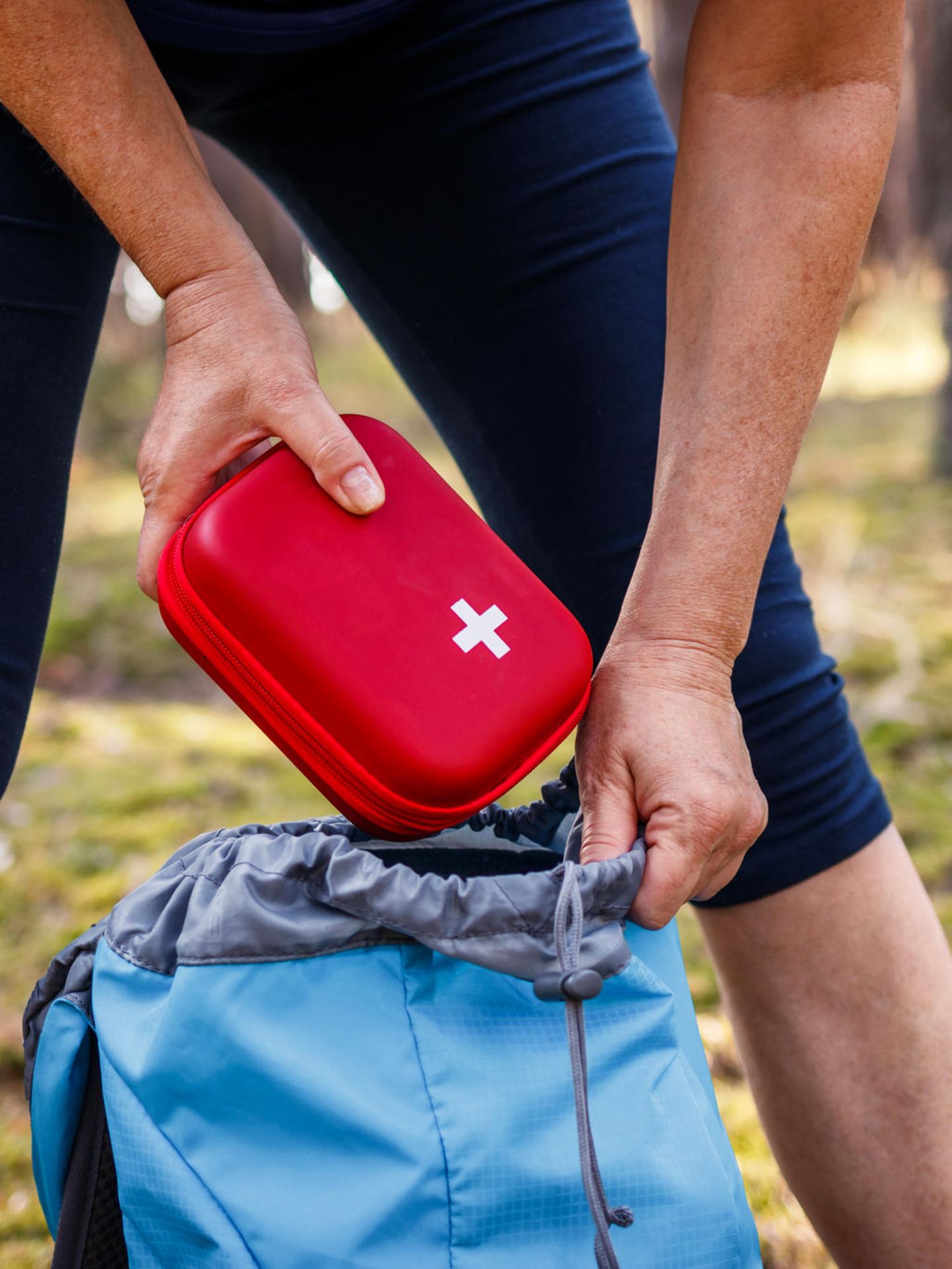 Frau nimmt Erste-Hilfe-Kasten aus dem Rucksack
