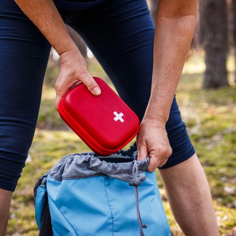 Frau nimmt Erste-Hilfe-Kasten aus dem Rucksack