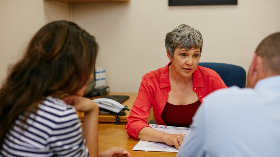 Frau sitzt mit Paar an einem Tisch und spricht, Symbolbild zum Thema Abtreibung