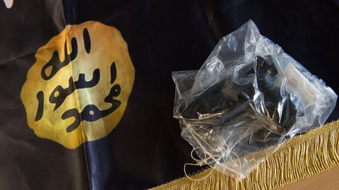Eine beschlagnahmte Waffe liegt auf einer IS-Flagge