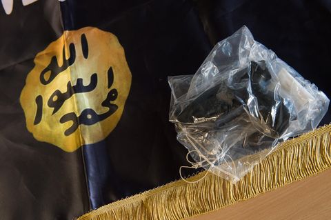 Eine beschlagnahmte Waffe liegt auf einer IS-Flagge