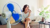 Frau sitzt mit Ventilator in der Wohnung