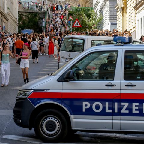 Ein Polizeiauto steht in der Nähe von versammelten "Swifties" in Wien