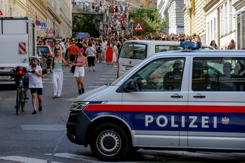 Ein Polizeiauto steht in der Nähe von versammelten "Swifties" in Wien