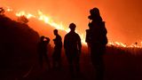 Vor einem Waldbrand in Griechenland sind die Konturen von Feuerwehrleuten zu sehen