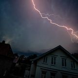 Blitze leuchten in der Nacht über den Wohnhäusern auf