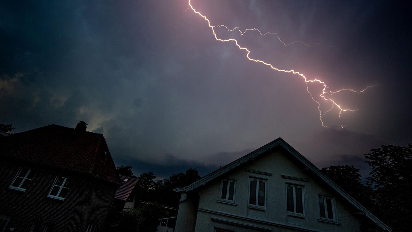 Blitze leuchten in der Nacht über den Wohnhäusern auf