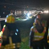 Blick über die Köpfe von Feuerwehrleuten hinweg auf den aufgefahrenen Zug