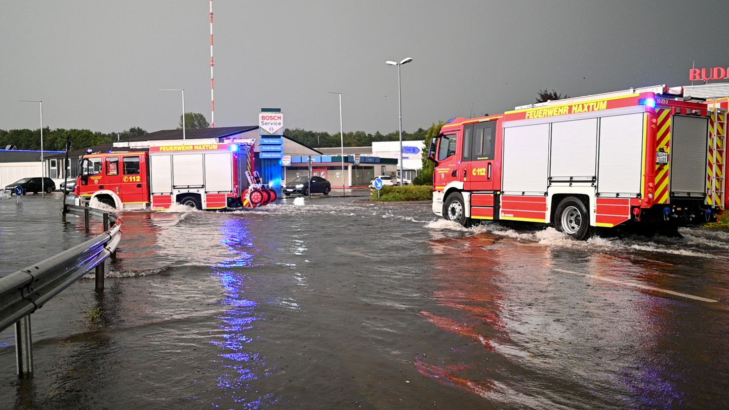 Zwei Feuerwehrautos fahren über ein überflutetes Tankstellen-Grundstück Zwei Feuerwehrautos fahren über ein überflutetes Tankstellen-Grundstück