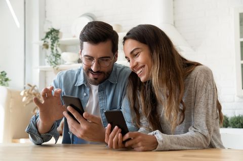 Smartphone kaufen: Ein Paar diskutiert am Küchentisch über ihre Smartphones.