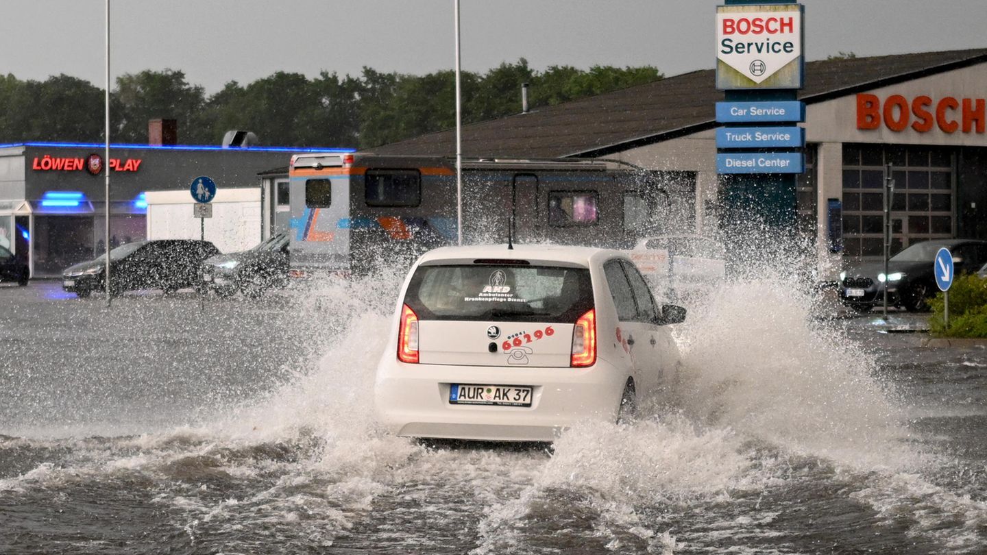 Ein Auto fährt durch eine großw Wasserpfütze, Gewitter sorgten in Deutschland für Überschwemmungen.