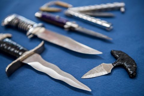 Messer und Stichwaffen, die unter das bisherige Messerverbot fallen, liegen auf blauem Tuch