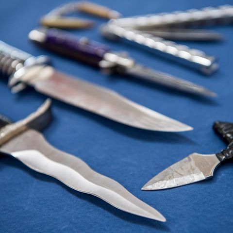 Messer und Stichwaffen, die unter das bisherige Messerverbot fallen, liegen auf blauem Tuch