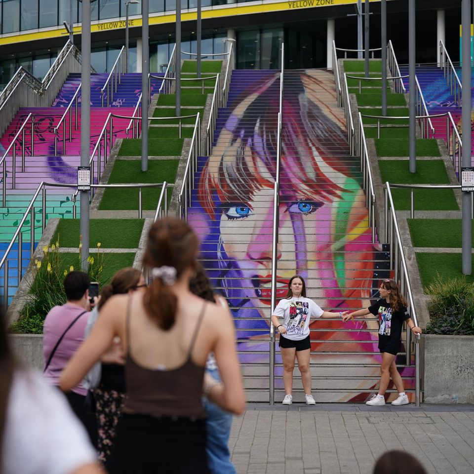 Auf einer Treppe in London ist Taylor Swifts Gesicht in bunten Farben gemalt, Fans machen Fotos