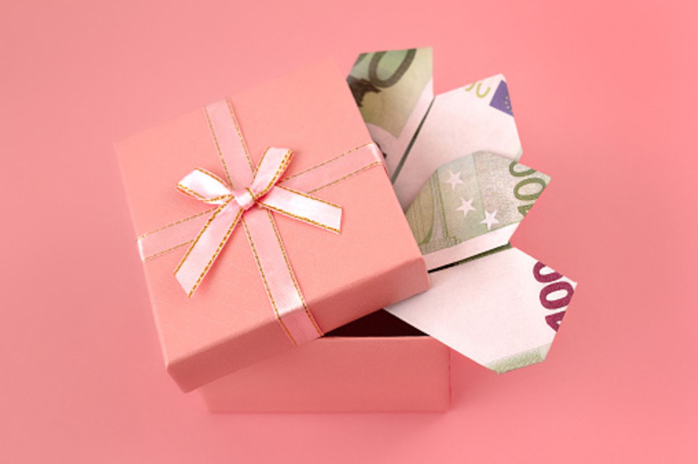 Geöffnete rosa Geschenkschachtel mit gefalteten 100 Euro Noten