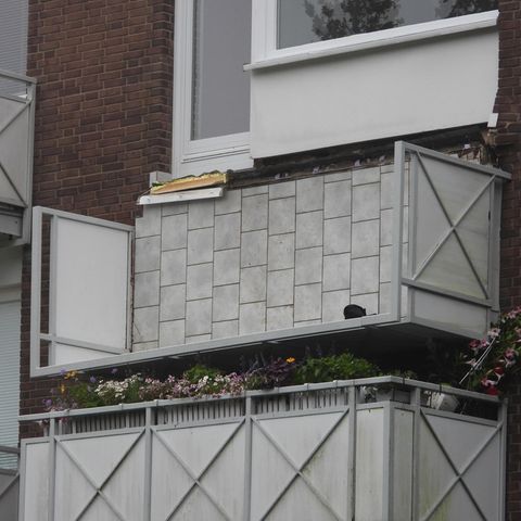 Umgeknickter Balkon hängt an der Hauswand herunter