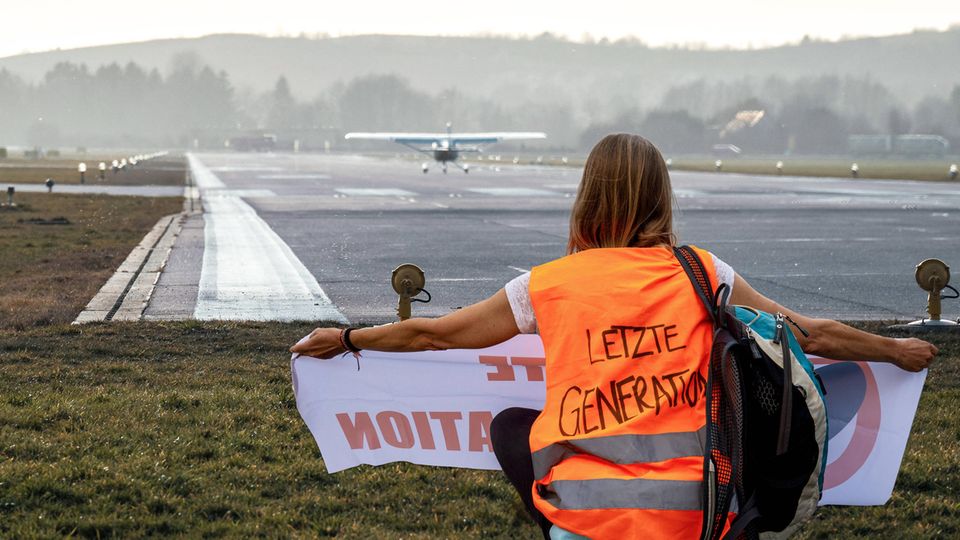 Eine Klimaaktivistin der Letzten Generation hat sich vor einer Landebahn auf einem deutschen Flughafen positioniert