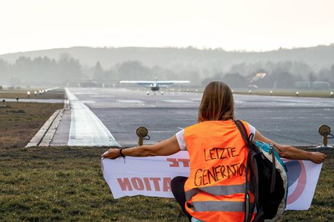 Eine Klimaaktivistin der Letzten Generation hat sich vor einer Landebahn auf einem deutschen Flughafen positioniert
