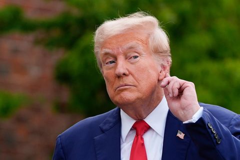 Donald Trump halt die Hand ans Ohr, so als wollte er besser hören