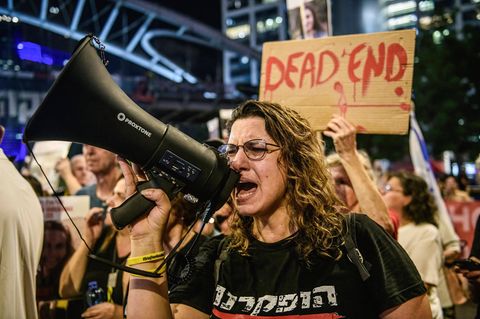 In Israel ruft eine Frau auf einer Demo für einen Waffenstillstand mit der Hamas etwas in ein Megafon