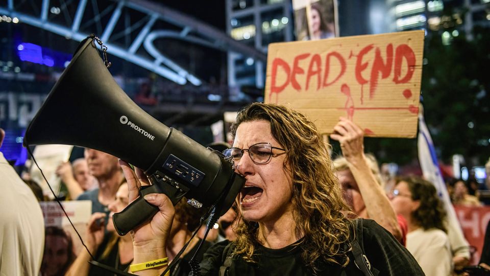 In Israel ruft eine Frau auf einer Demo für einen Waffenstillstand mit der Hamas etwas in ein Megafon