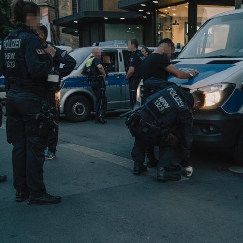 Messertaskforce: Ein junger Mann wird an einem Polizeiauto von einem Polizisten abgetastet