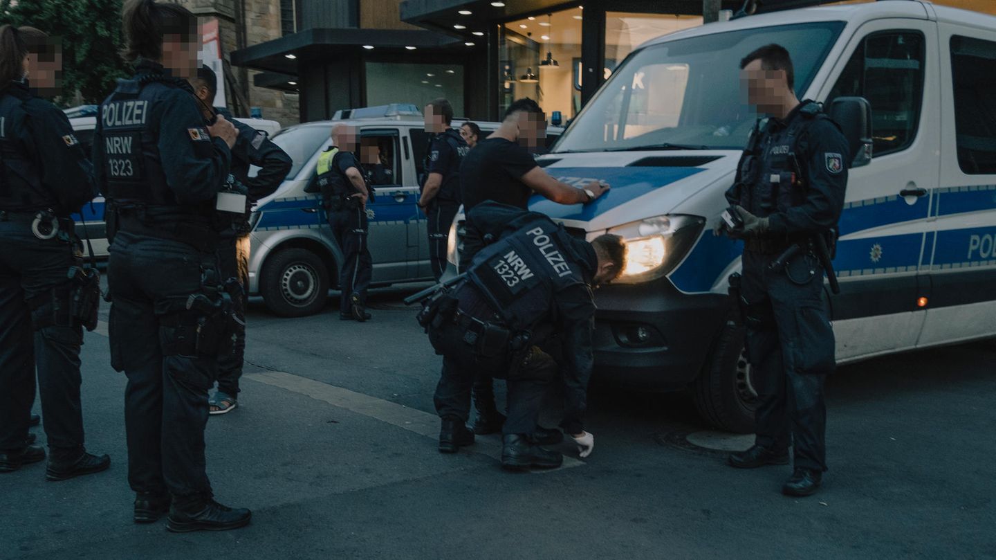 Messertaskforce: Ein junger Mann wird an einem Polizeiauto von einem Polizisten abgetastet Messertaskforce: Ein junger Mann wird an einem Polizeiauto von einem Polizisten abgetastet