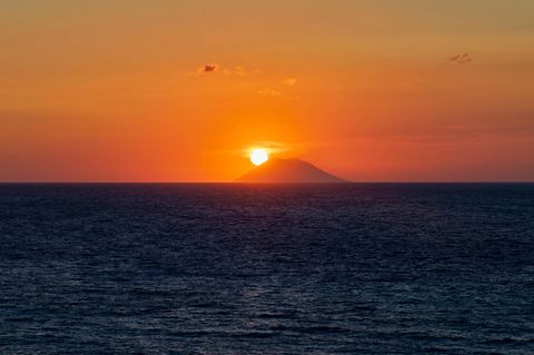 Die Sonne versinkt hinter dem italienischen Vulkan Stromboli