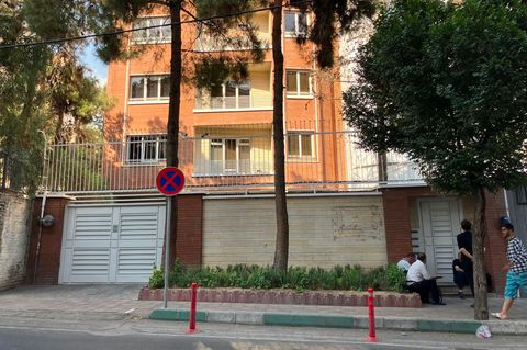 In der Mauer des Deutsche Sprachinstitut im Iran sind eine weiße Lamellentür sowie eine Hofeinfahrt zu sehen