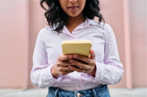 Very demure: Eine Frau in Bluse an ihrem Handy