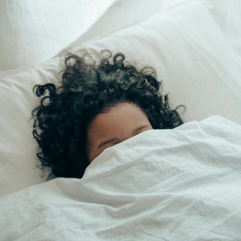 Schlafstörung: Eine junge Frau mit dunklen lockigen Haaren liegt im Bett