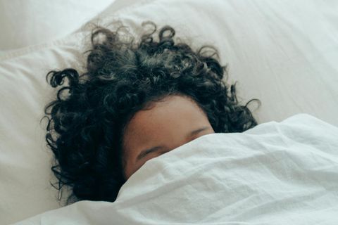 Schlafstörung: Eine junge Frau mit dunklen lockigen Haaren liegt im Bett