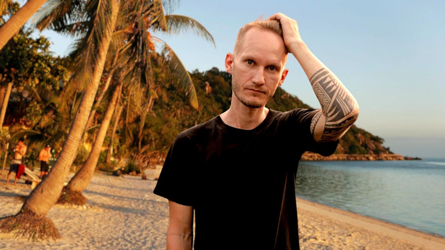 Ein junger Mann steht an einem tropischen Strand in Thailand