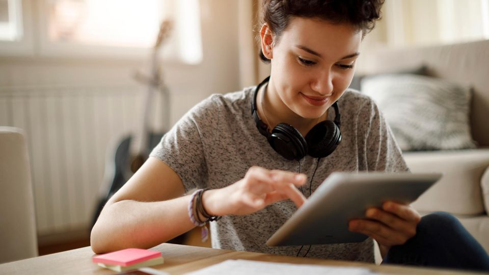 Junge Studentin nutzt ein Tablet zum Arbeiten am Schreibtisch