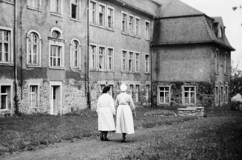 DDR: Zwei Krankenschwestern gehen entlang einer "Tripperburg"
