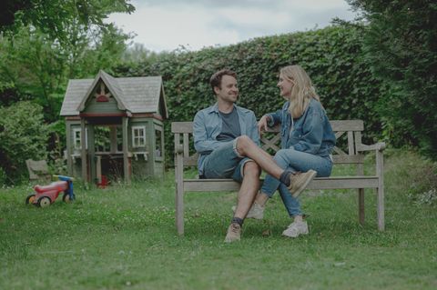 Laura Kverneland und ihr Mann Anders Handrup Kverneland sitzen auf einer Holzbank.