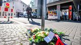 In der Nähe des Tatorts liegen Blumen auf einem Gehweg