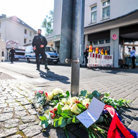 In der Nähe des Tatorts liegen Blumen auf einem Gehweg