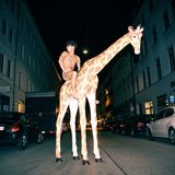 Nackter Simon Lohmeyer auf Plastikgiraffe