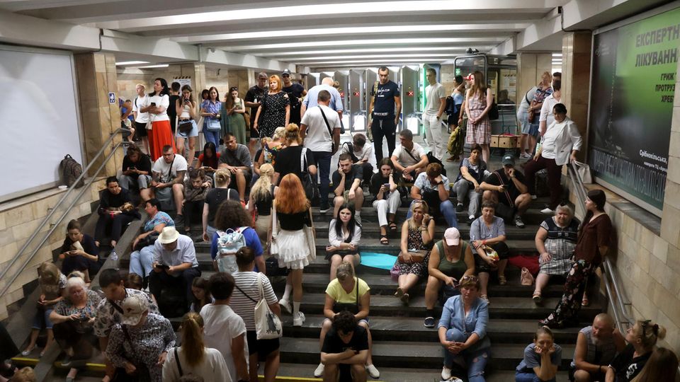 In der Ukraine sitzen Menschen auf der Treppe der U-Bahn-Station Osokorky in Kiew